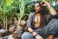 Fashion guy with dreadlocks in tropical coconut palms smiling