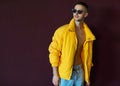 Fashion guy standing near a viola wall in yellow clothing