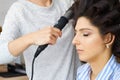 Fashion hairdresser doing hairstyle to young woman client making perm professional styler for curl. Royalty Free Stock Photo