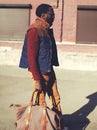 Fashion handsome stylish african man wearing a vest jacket, sweater and bag walking in city