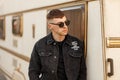 Fashion handsome young guy in sunglasses in a black denim jacket Royalty Free Stock Photo