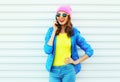 Fashion happy cool smiling girl talking on smartphone in colorful clothes over white background wearing pink hat yellow sunglasses Royalty Free Stock Photo