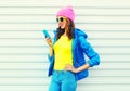 Fashion happy cool smiling girl using smartphone in colorful clothes over white background wearing a pink hat yellow sunglasses Royalty Free Stock Photo