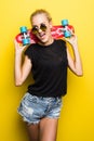 Fashion happy smiling hipster cool girl in sunglasses with skateboard having fun outdoors against the yellow background Royalty Free Stock Photo