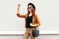 Fashion happy young smiling woman taking photo picture self-portrait on smartphone wearing retro elegant hat, sunglasses