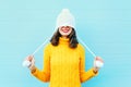 Fashion happy young woman in knitted hat and sweater having fun over colorful blue Royalty Free Stock Photo