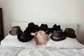 fashion hats positioned around a white cushion on a bed