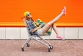 Fashion hipster cool girl with skateboard in shopping cart