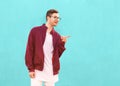 Fashion hipster guy in glasses poses near the wall the color of Royalty Free Stock Photo