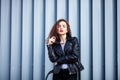 Fashion hipster woman posing outdoor. leather jacket,brunette hair, bright red lips, sunglasses.Street fashion concept. Royalty Free Stock Photo