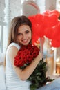 Fashion interior photo of beautiful smiling woman with dark hair holding a big bouquet of red roses in Valentine`s day Royalty Free Stock Photo