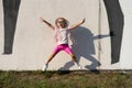 Fashion kid concept - stylish little girl child jumping, wearing bright clothes and sunglasses against the white wall. Royalty Free Stock Photo