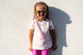 Fashion kid concept - stylish little girl child wearing bright clothes and sunglasses against the white wall. Royalty Free Stock Photo