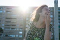 Fashion lady laughing with open mouth and hand in front in the street and sunlight. Happy adolescent showing tooth after a joke