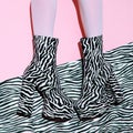 Fashion legs in heel party zebra boots on minimal pink background. Animal texture print. Stylish tropical concept