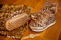 Fashion Leopard sneakers with Glamour golden wristwatch and purse on wooden background.