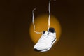 Fashion and Lifestyle Concepts. New White Sneakers With Flying Shoelaces Placed Over Yellow Background With Circular Spotlight