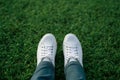 Fashion lifestyle Feet in white sneakers on lush green grass
