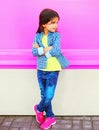 Fashion little girl child posing on city street on colorful pink wall