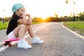 Fashion little girl child sitting on skateboard in city, wearing a sunglasses and t-shirt. Royalty Free Stock Photo