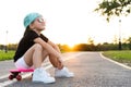 Fashion little girl child sitting on skateboard in city, wearing a sunglasses and t-shirt. Royalty Free Stock Photo