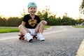 Fashion little girl child sitting on skateboard in city, wearing a sunglasses and t-shirt. Royalty Free Stock Photo