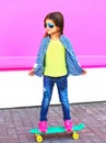 Fashion little girl child on skateboard in city on colorful pink wall Royalty Free Stock Photo