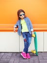 Fashion little girl child with skateboard wearing a sunglasses and checkered shirt over orange Royalty Free Stock Photo