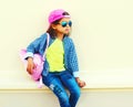 Fashion little girl child wearing sunglasses, baseball cap, backpack on city street on white Royalty Free Stock Photo