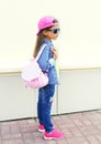 Fashion little girl child wearing a sunglasses, baseball cap and backpack standing in profile over white Royalty Free Stock Photo