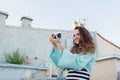 Fashion look, pretty cool young woman model with retro film camera. curly hair outdoors. Stylish girl photographer takes the old c Royalty Free Stock Photo