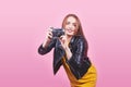 Fashion look, pretty cool young woman model with retro film camera wearing a black jacket, against pink background with Royalty Free Stock Photo