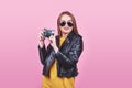 Fashion look, pretty cool young woman model with retro film camera wearing a black jacket, against pink background with Royalty Free Stock Photo