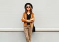 Fashion look, pretty young woman wearing a retro elegant hat, sunglasses, brown jacket and black handbag clutch Royalty Free Stock Photo