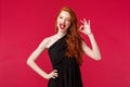 Fashion, luxury and beauty concept. Portrait of pleased sassy good-looking redhead woman in black prom dress, wink