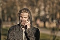 Fashion macho smiling with smartphone in casual sweatshirt. Happy guy in hood talk on mobile phone on sunny outdoor Royalty Free Stock Photo