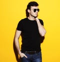 Fashion male posing on yellow background in studio in sunglasses. Royalty Free Stock Photo
