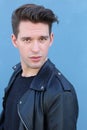 Fashion man, Handsome serious beauty male model portrait wearing leather jacket, young guy over blue background Royalty Free Stock Photo