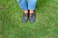 Fashion Man is Legs in Blue Jeans and Wear Vintage Shoes on Green Grass Background