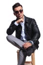 Fashion man wearing sunglasses sits cross-legged on wooden chair Royalty Free Stock Photo