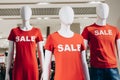 Fashion Mannequins in red T-shirts and text sale stand in shop window and attract shoppers. Black friday sale in casual store Royalty Free Stock Photo