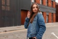 Fashion model american young pretty hipster woman in stylish denim jacket walks in the city. Fashionable urban girl in jeans Royalty Free Stock Photo