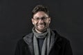 Fashion model with beard smile on dark background. Happy man in glasses on bearded face. Bearded man in scarf and coat Royalty Free Stock Photo