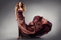 Fashion Model in Black Dress flying on Wind. Beauty Woman with Curly Long Hair in Evening Gown. Elegant Lady dancing in Luxury Royalty Free Stock Photo