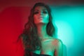 Fashion model brunette woman in colorful bright neon lights posing in studio. Beautiful girl, trendy glowing makeup Royalty Free Stock Photo