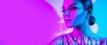 Fashion model brunette woman in colorful bright neon lights posing in studio. Beautiful girl, trendy glowing makeup Royalty Free Stock Photo