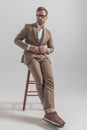 Fashion model closing his jacket, crossing his legs, looking away Royalty Free Stock Photo