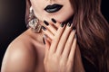 Fashion model with dark make-up, long hair and black and silver trendy manicure wearing jewellery. Black lipstick