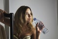 Fashion model drinking water from bottle in studio