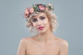 Fashion model with flowers. Cheerful blonde woman with short haircut and makeup on blue background Royalty Free Stock Photo